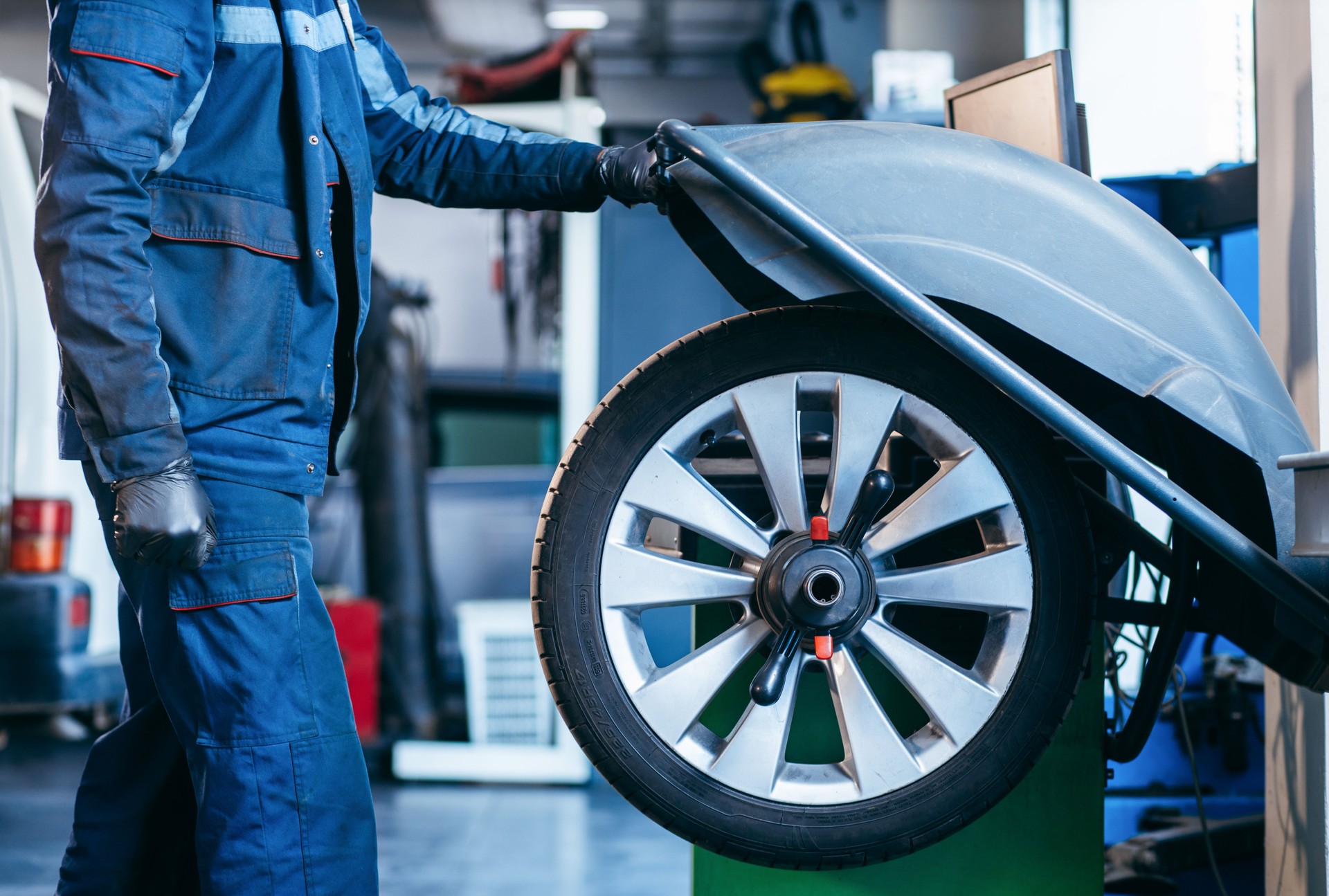 Auto mechanic uses tire balancing machine and turning tire